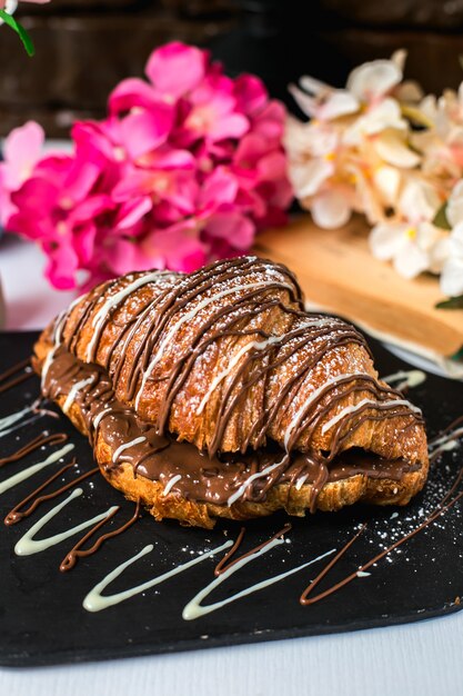 Vista lateral de croissant al horno con chocolate sobre una plancha de madera