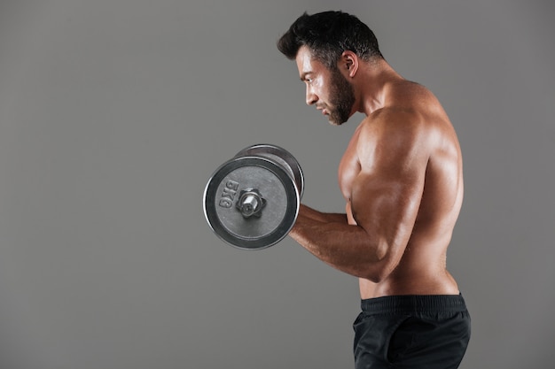 Vista lateral de un culturista masculino serio sin camisa fuerte