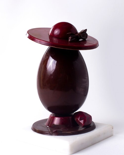 Vista lateral decorado huevo de chocolate con un sombrero y un corazón de chocolate en el stand