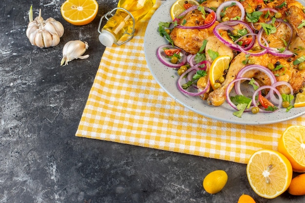 Vista lateral de la deliciosa cena plato de pollo frito con varias especias y alimentos ajos botella de aceite caída limón en el lado izquierdo sobre fondo de color oscuro