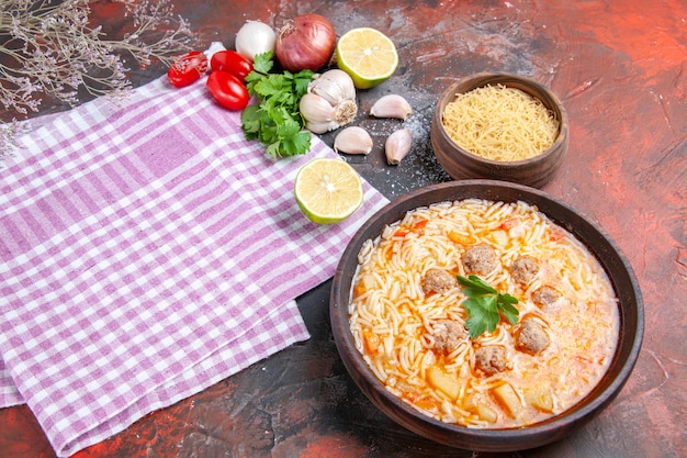 Foto gratuita vista lateral de una deliciosa sopa de pollo con fideos verdes y una cuchara en una toalla despojada rosa botella de aceite ajo tomates limón y cuaderno sobre fondo oscuro