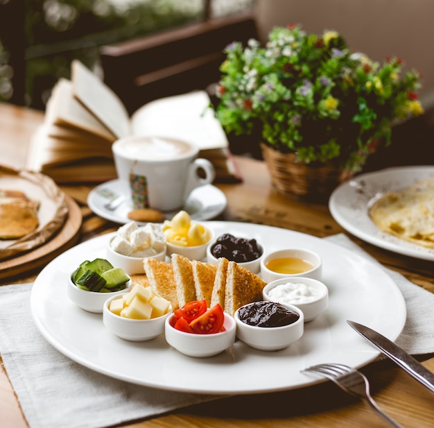 Vista lateral desayuno bocadillos con tostadas fritas tomate pepino mermeladas mantequilla miel quesos