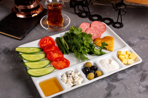Vista lateral del desayuno turco tradicional con aceitunas queso feta miel verduras y té
