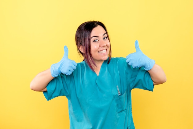 Vista lateral de un doctor sonriente médico en los guantes médicos está hablando de la importancia de los guantes