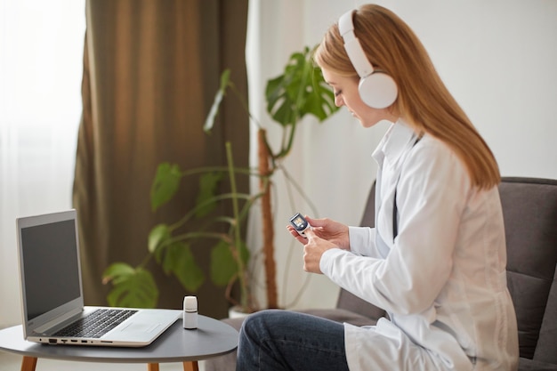 Foto gratuita vista lateral de la doctora del centro de recuperación de covid con auriculares demostrando cómo usar el oxímetro