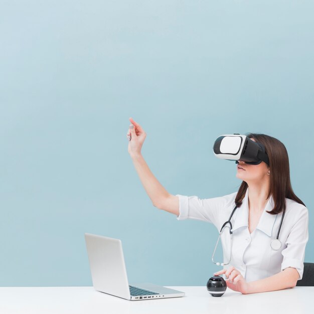 Vista lateral de la doctora con estetoscopio con casco de realidad virtual