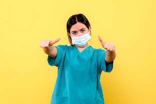 Vista lateral de una doctora con máscara se alegra de haber curado a pacientes con coronavirus