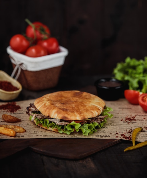 Vista lateral de doner kebab con papas fritas en una tabla para cortar madera