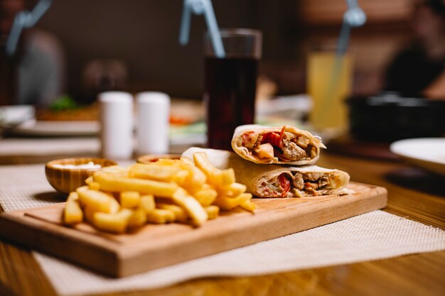 Vista lateral doner de pollo en pan de pita con papas fritas con salsa de tomate y mayonesa en el tablero