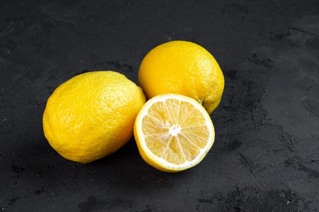 Vista lateral de dos limones enteros con una rodaja de limón picado