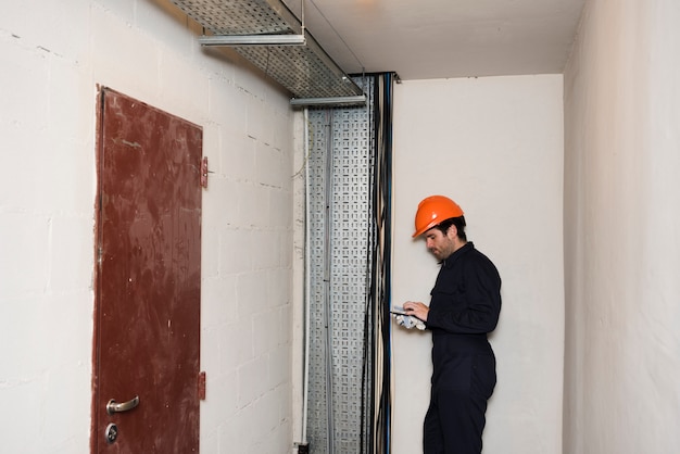 Vista lateral de un electricista masculino usando un teléfono móvil en el trabajo