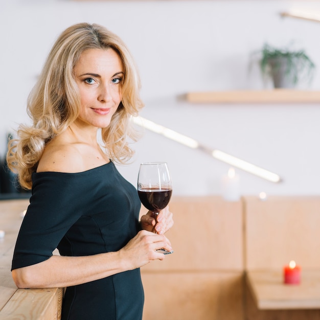 Vista lateral de la encantadora mujer sosteniendo una copa de vino
