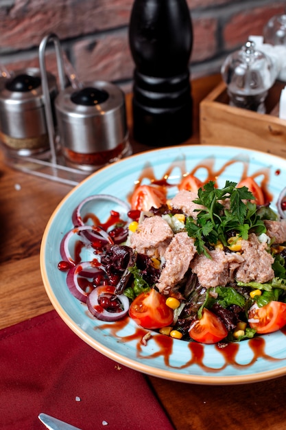 Foto gratuita vista lateral de ensalada de atún con cebolla roja y tomates en un plato