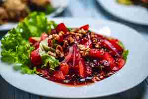 Foto gratuita vista lateral ensalada georgiana con rodajas de tomate cebolla roja nuez salsa de ciruelas y lechuga en un plato