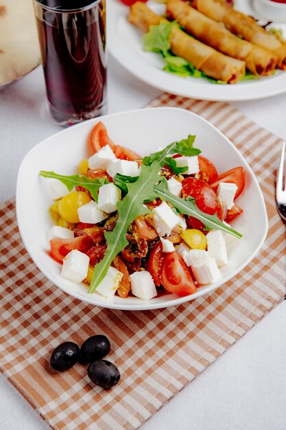 Vista lateral de ensalada con tomate feta y rúcula