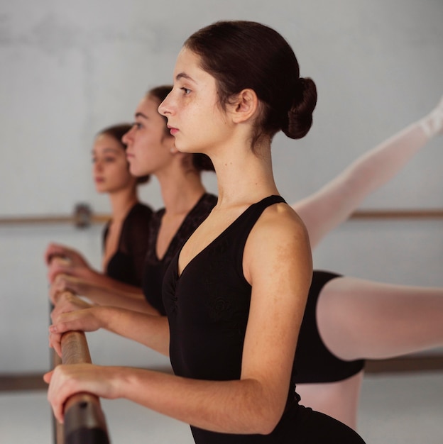 Foto gratuita vista lateral del entrenamiento de bailarinas profesionales en leotardos