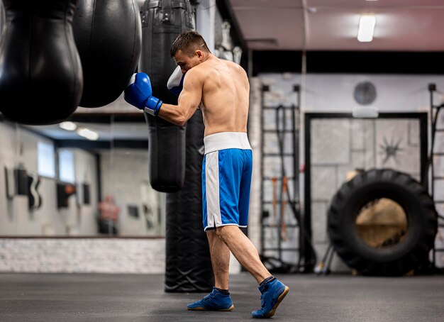 Vista lateral del entrenamiento de boxeador masculino con guantes protectores