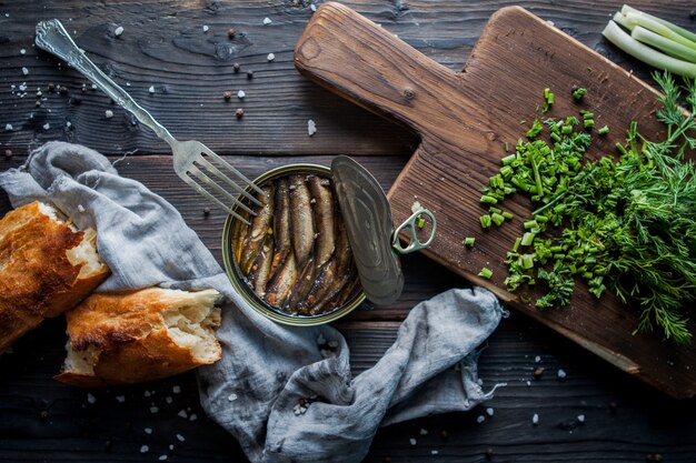 Vista lateral espadín enlatado con verduras picadas y tenedor y tabla de cortar