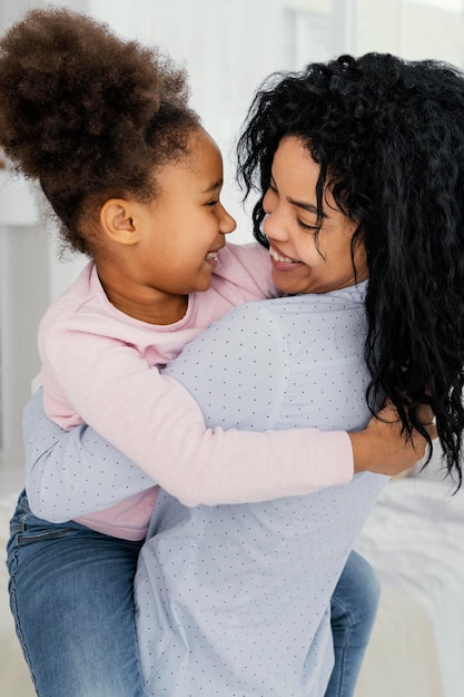 Foto gratuita vista lateral de la feliz madre sosteniendo a su hija sonriente