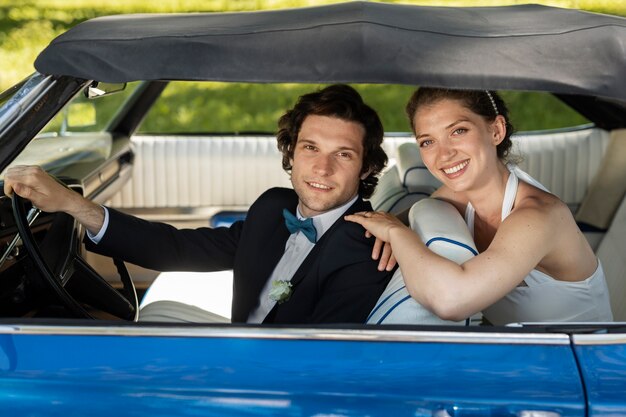 Vista lateral feliz pareja casada en coche azul
