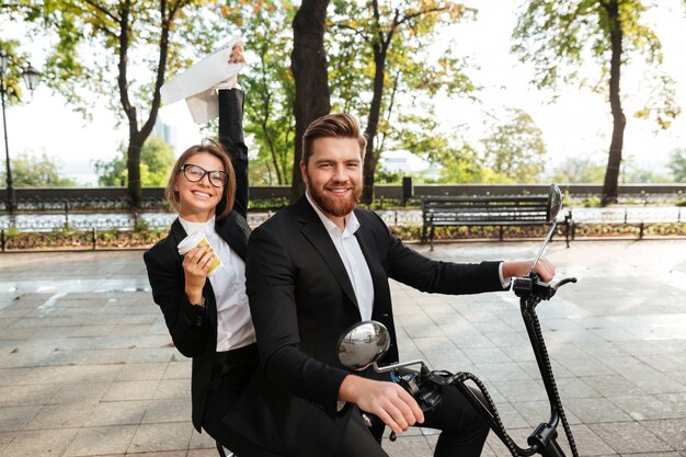 Vista lateral de la feliz pareja elegante paseos en moto moderna