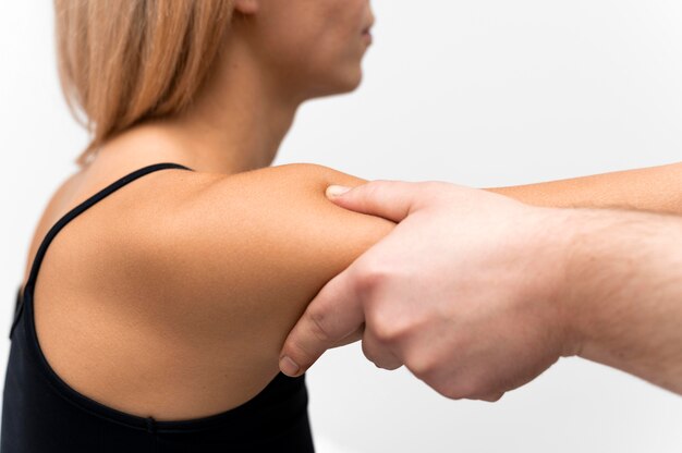 Vista lateral del fisioterapeuta masajeando el brazo de la mujer