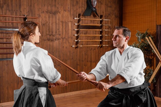 Vista lateral de la formación de instructores de artes marciales masculinas en la sala de prácticas con una joven aprendiz