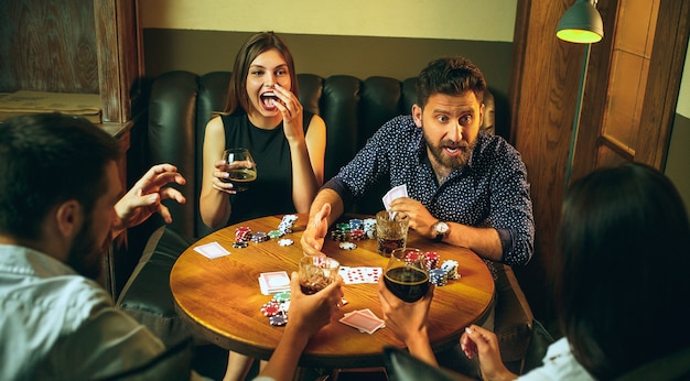 Vista lateral foto de amigos sentados en la mesa de madera. Amigos divirtiéndose mientras juegan juegos de mesa.