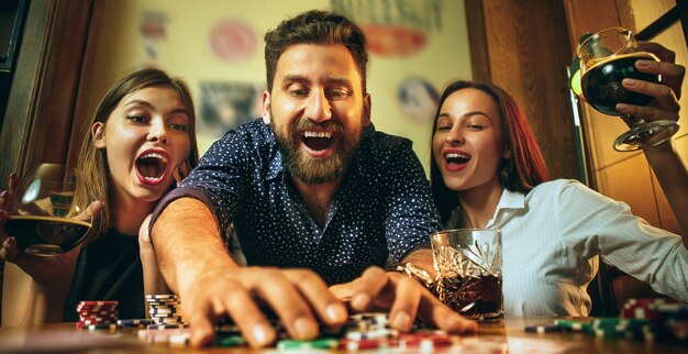 Vista lateral foto de amigos sentados en la mesa de madera. Amigos divirtiéndose mientras juegan juegos de mesa.