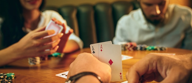 Foto gratuita vista lateral foto de amigos sentados en la mesa de madera. amigos divirtiéndose mientras juegan juegos de mesa.