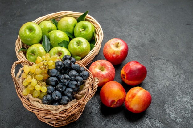 Vista lateral frutas cestas de madera de manzanas verdes y racimos de coloridas uvas nectarinas