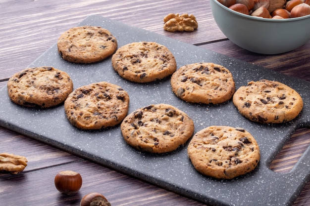 Vista lateral de galletas de avena con chocolate en un tablero con nueces