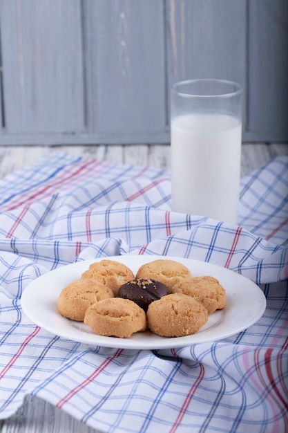 Vista lateral de galletas en un plato blanco servido con un vaso de leche