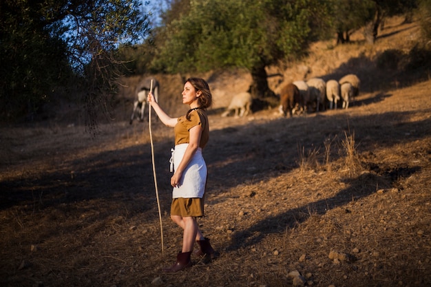 Foto gratuita vista lateral del granjero de sexo femenino que sostiene el palillo en el campo