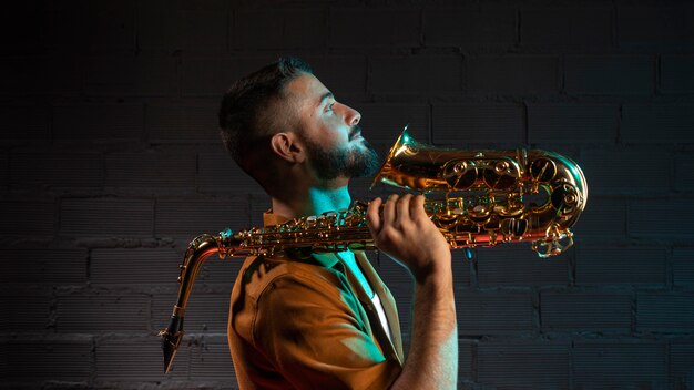 Vista lateral del guapo músico con saxofón