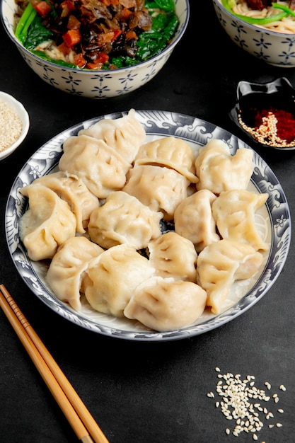 Vista lateral de gyoza con salsa de soja y palillos en un plato