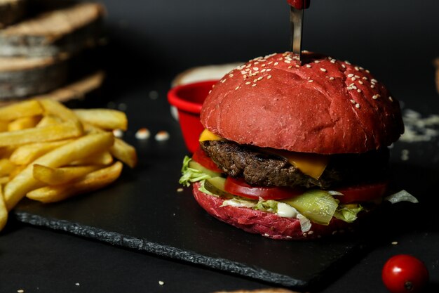 Vista lateral hamburguesa de carne con papas fritas y salsa en un stand