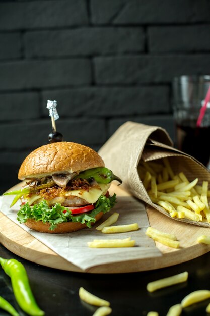 Vista lateral hamburguesa con papas fritas y pimiento verde en pizarra