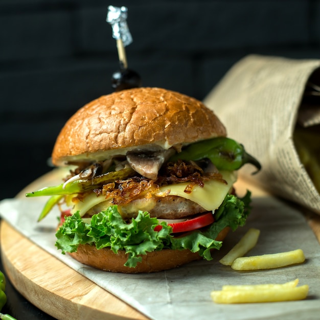 Foto gratuita vista lateral hamburguesa de pollo con papas fritas en la pizarra