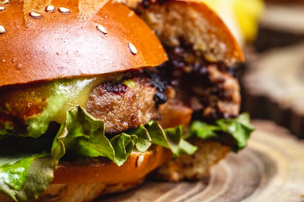 Vista lateral hamburguesa con queso empanada de carne a la parrilla con queso y lechuga entre bollos de hamburguesa