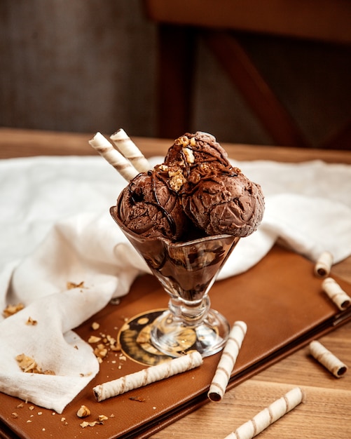 Vista lateral helado de chocolate con nueces y rollos de obleas