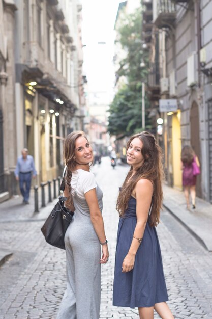 Vista lateral de hermosas mujeres jóvenes de pie en la calle
