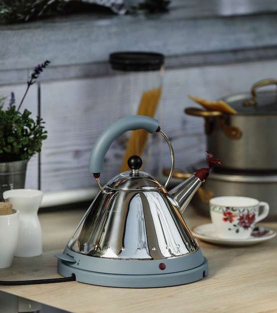 Foto gratuita vista lateral del hervidor eléctrico moderno con silbato en una mesa de madera en la cocina