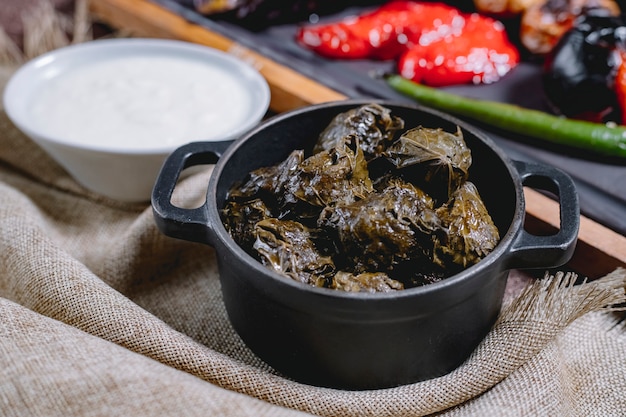 Foto gratuita vista lateral de hojas de parra rellenas de dolma con carne molida cebolla verde y yogur sobre la mesa