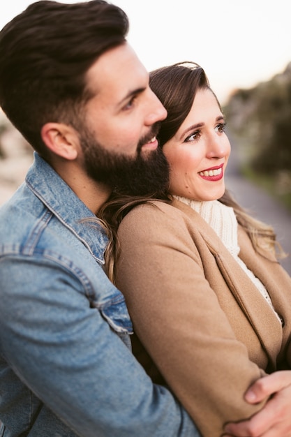 Foto gratuita vista lateral hombre abrazando a mujer y mirando a otro lado