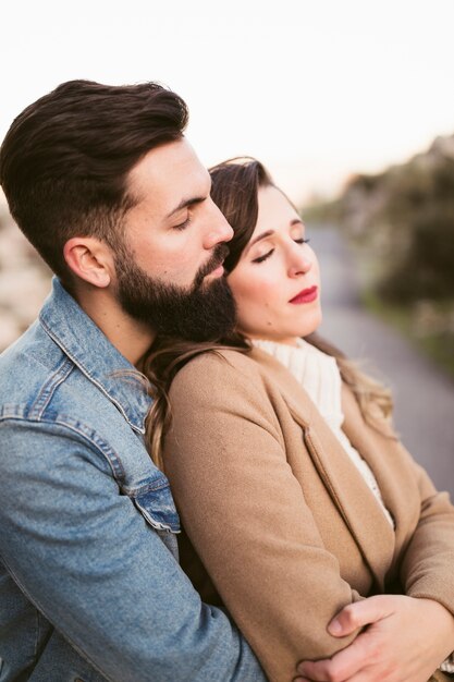 Vista lateral hombre abrazando a mujer con los ojos cerrados