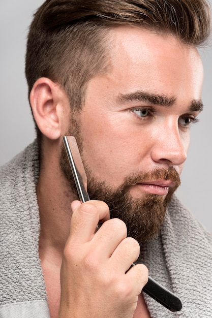 Vista lateral del hombre afeitándose la barba