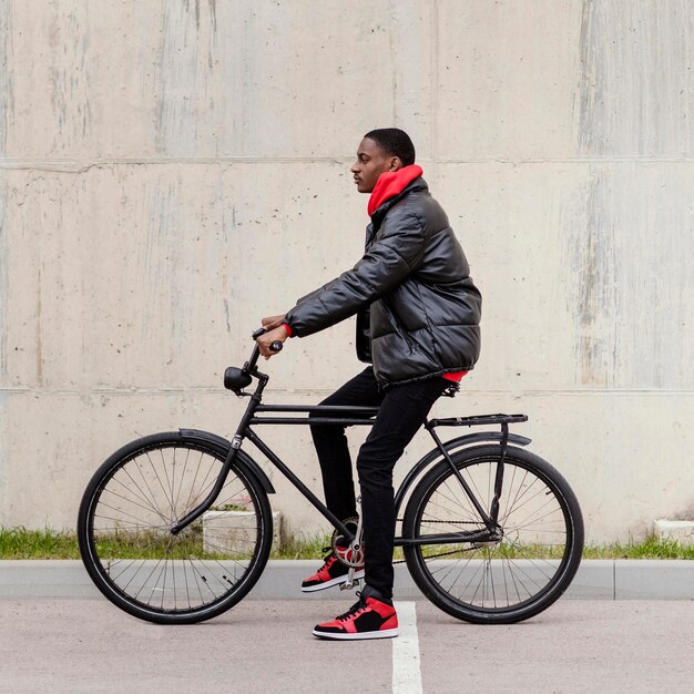 Vista lateral del hombre afroamericano y su bicicleta