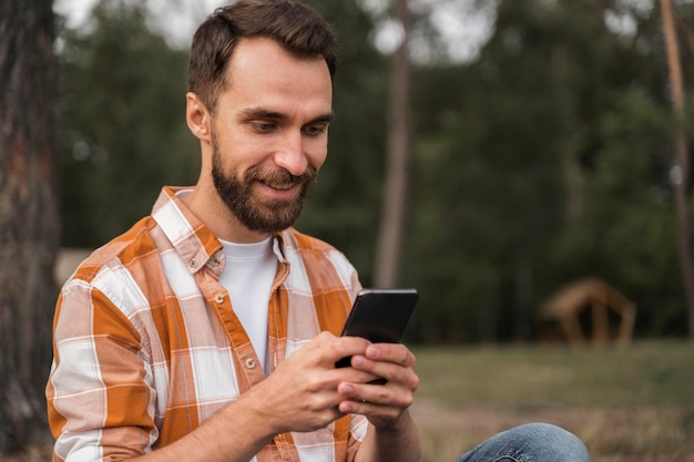 Vista lateral del hombre al aire libre mirando smartphone