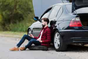 Foto gratuita vista lateral del hombre apoyado en el auto